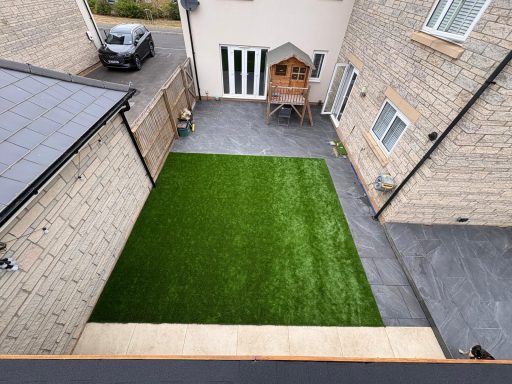 Artificial grass lawn with grey paved borders in a landscaped garden in Weston-Super-Mare.