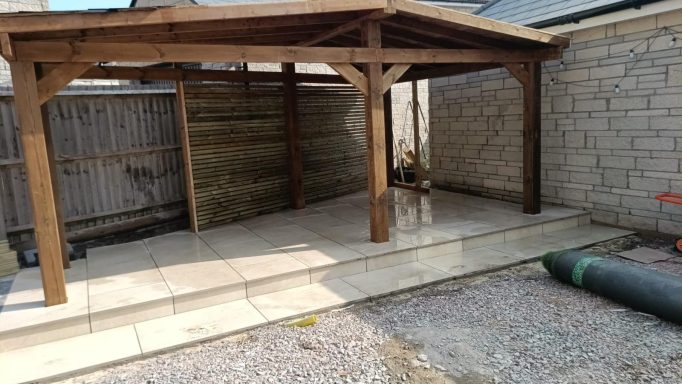 Bespoke timber pergola with a covered seating area, porcelain patio and artificial grass in Weston-Super-Mare.